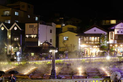 Illuminated buildings by street in city at night