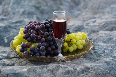 Wine and grapes in container on rock