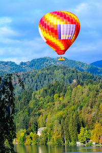 Hot air balloon flying over mountain against sky