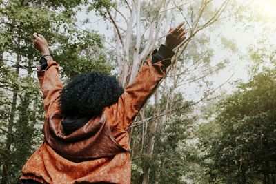 Woman with arms upraised getting the sun in the forest