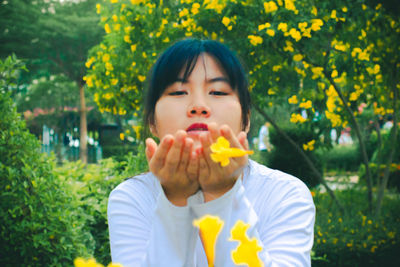 Woman blowing yellow flowers in garden