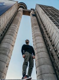 Low angle view of man standing by buildings against sky