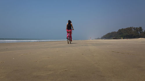 Rear view of woman riding on beach