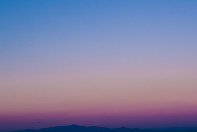 Scenic view of silhouette mountains against clear sky at sunset