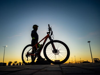 Man riding bicycle on street against sky