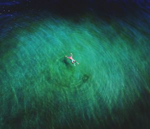 High angle view of shirtless man floating on sea