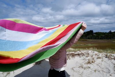 Low section of person standing on field with multicolored towel