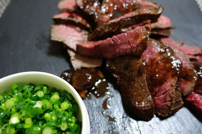 High angle view of meat with spring onions on serving tray