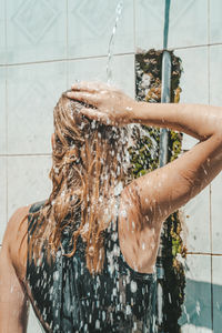 Rear view of woman taking shower outdoors