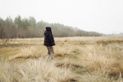 Woman standing on field in foggy weather