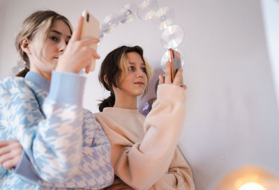 Low angle view of mother and daughter using mobile phone