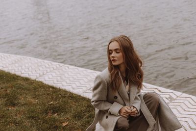 Portrait of young woman standing against lake