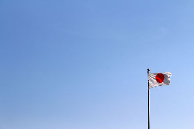 Low angle view of flag against clear blue sky