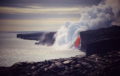 Waves splashing on shore against sky