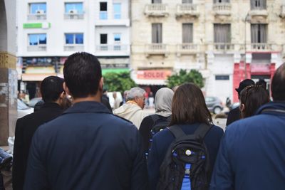 Rear view of people standing against buildings in city