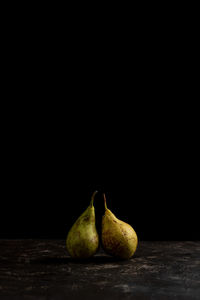 Close-up of pears on table against black background