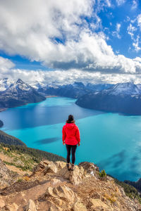 Rear view of man standing on mountain against sky