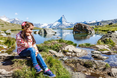 Full length of woman sitting on rock against mountain