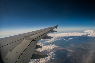 Airplane flying over clouds against blue sky