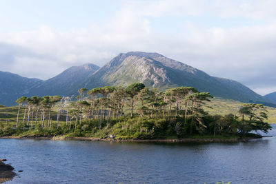 Scenic view of lake, island, and mountains against cloudy sky