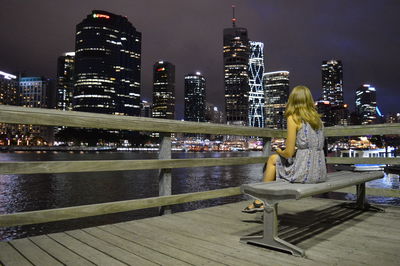 Woman looking at illuminated city during night
