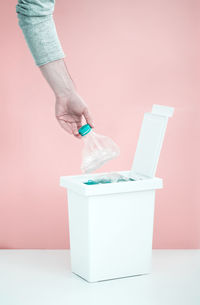 Low angle view of woman hand holding bottle against wall