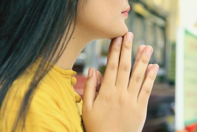 Midsection of woman with hands clasped praying