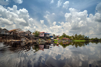 Buildings by lake against sky