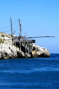 Sailboat on sea against clear blue sky