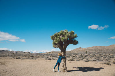 Full length of woman hugging tree at death valley national park against sky