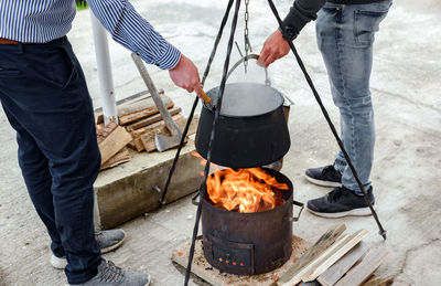 Friends cooking stew in cast iron boiler over fire