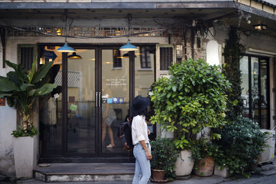 Rear view of woman standing by building in city