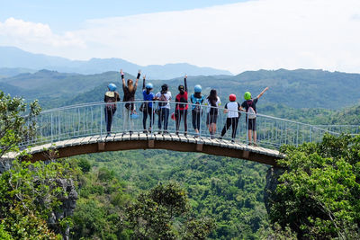 People on bridge against sky