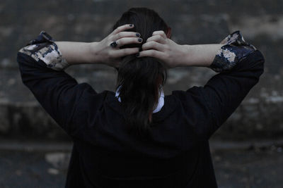 Rear view of man tying hair