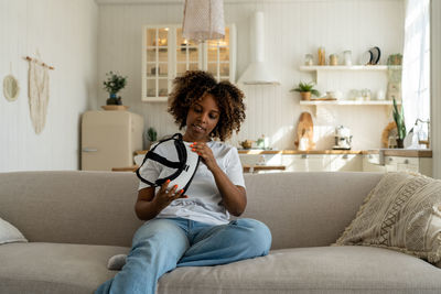 Young woman using digital tablet while sitting on sofa at home