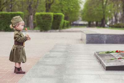 Baby girl in soviet military uniform lays a flower on a monument to those killed in world war ii