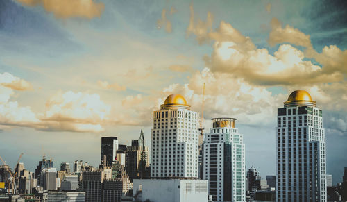 Buildings in city against cloudy sky