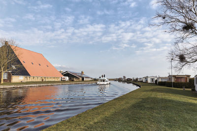 Canal by building against sky