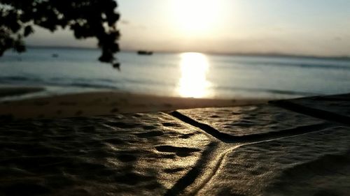 Close-up of sand at beach against sky during sunset