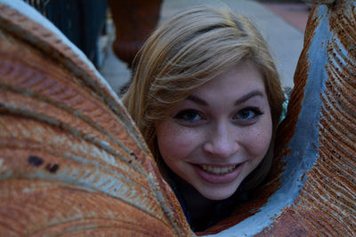 High angle portrait of smiling young woman by rusty metal