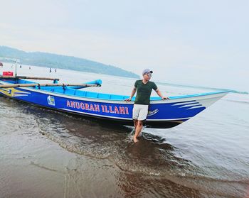 Man standing on boat in sea against sky