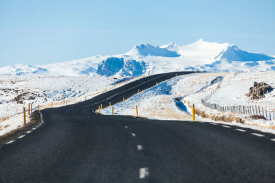 Empty road leading towards snowcapped mountains