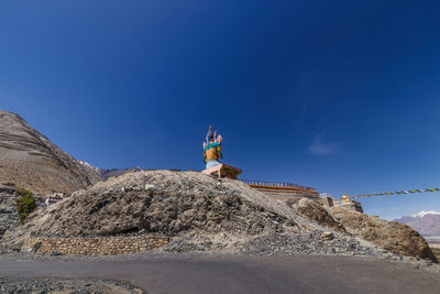 Rear view of man standing on mountain against clear blue sky