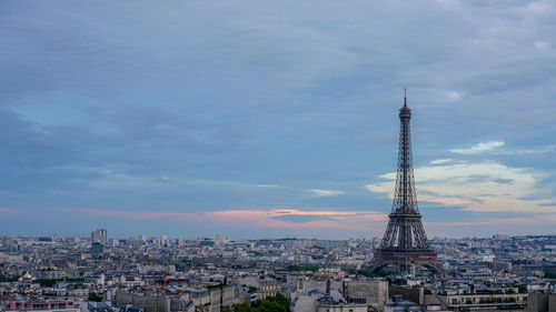 Aerial view of buildings and eiffel tower in city against cloudy sky