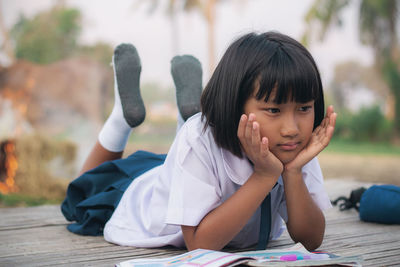 Thoughtful schoolgirl lying outdoors