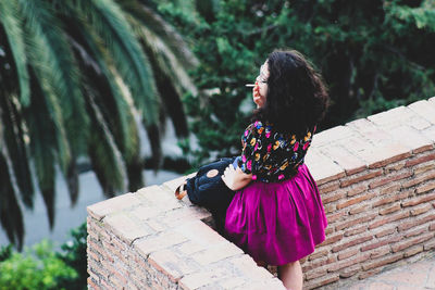 Woman looking away while sitting on plant