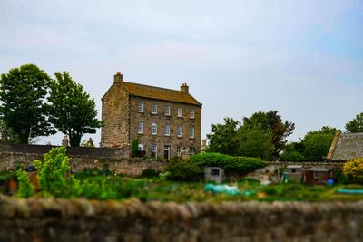 Old building by trees against sky