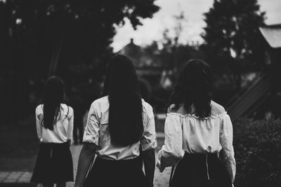 Rear view of friends standing on footpath