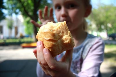 Close-up of girl holding bread outdoors