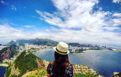 Rear view of woman standing on mountain by sea against sky